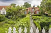 Ein Haus mit üppigem Garten, im Hintergrund ist ein Kirchturm zu sehen
