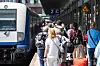 Reisende gehen auf der Nordseeinsel im Bahnhof Westerland an einem Zug der Deutschen Bahn entlang.