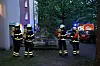 Einsatzkräfte der Feuerwehr stehen vor dem Mehrfamilienhaus.