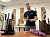Mann prüft in einer Werkstatt Messer an einem Arbeitstisch mit geschnittenen roten Zwiebeln.