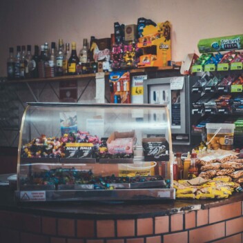 Kiosk mit Glasvitrine, Snacks, Süßwaren und Getränken in Regalen und Kühlschränken.