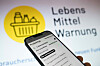 Handy vor Bildschirm „Lebensmittelwarnung“