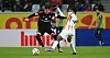 Nicolás Capaldo vom HSV im Zweikampf mit Johan Manzambi von Freiburg vor einer TV-Kamera von DAZN