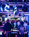 DJs stehen vor einer Menschenmenge unter blau-violetter Beleuchtung in einem Parkhaus.