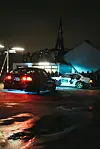 Zwei Fahrzeuge driften auf dem dem obersten Parkdeck umgeben von Zuschauern.