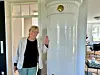 Eine Frau steht neben einem weißen Kachelofen.
