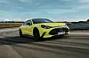 Gelber Mercedes-AMG GT 4-Türer fährt auf einer Teststrecke. Die elektrische Limousine zeigt den großen Panamericana-Grill und die flache Coupé-Silhouette.