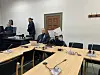 Rene P. sitzt mit einer weißen Mappe vor dem Gesicht neben seinem Verteidiger.