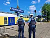 Zwei Polizisten stehen am Bahnhof Hamburg-Harburg neben einem vorbeifahrenden Regionalzug.