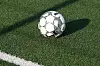 Ein Fußball liegt auf einem Kunstrasenfeld