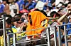 Ein Fan sitzt mit orangefarbener Warnweste über dem Kopf auf einer Tribüne