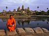 Ein buddhistischer Mönch sitzt vor der Tempelanlage Angkor Wat in Kambodscha am Wasserufer.