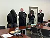 Die Angeklagten stehen mit verdeckten Gesichtern neben ihren Verteidigern.