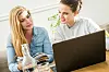 Zwei Frauen buchen eine Reise online.