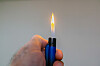Ein Mann hält ein Feuerzeug mit offener Flamme in der Hand.
