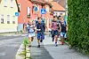 Kinder rennen an einer Straße entlang.