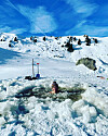 Ein Mann schwimmt in einem Eisloch.