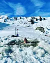 Ein Mann schwimmt in einem Eisloch.