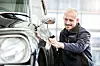 in Mann poliert einen schwarzen Oldtimer in einer Werkstatt und bereitet einen Citroën DS auf die neue Saison vor.