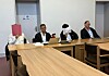 Die Angeklagten sitzen neben ihren Verteidigern und verdecken ihre Gesichter.