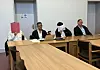 Die Angeklagten sitzen neben ihren Verteidigern und verdecken ihre Gesichter.