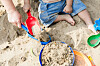 Ein Kind spielt im Sandkasten. (Symbolbild)