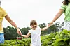 Vater, Mutter und Tochter auf einem Erdbeerfeld.