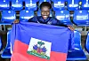 Haiti-Fan hält in Hamburg eine haitianische Flagge vor blauen Stadionsitzen