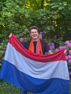 Niederlande-Fan mit Brille hält eine niederländische Flagge im Garten