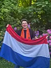 Niederlande-Fan mit Brille hält eine niederländische Flagge im Garten