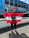 Österreich-Fan hält vor der Barclays Arena eine rot-weiße Flagge mit österreichischem Bundesadler