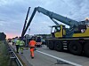 Einsatzkräfte und Schwerlastkran bei der Bergung eines umgekippten Sattelzugs auf der A7.