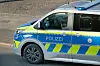 Deutscher Polizeiwagen mit Blaulicht und gelb-blauer Streifenlackierung auf der Straße.