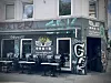 Geschlossenes Café mit „Torrefaktum“-Logo, leeren Tischen und Stühlen sowie Graffiti an der Fassade.