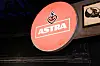 Rundes rotes ASTRA-Logo mit Herzsymbol an dunkler Fassade.
