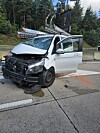 Stark beschädigter weißer Pkw mit eingedrückter Front steht nach einem Unfall auf der Straße.