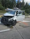 Stark beschädigter weißer Pkw mit eingedrückter Front steht nach einem Unfall auf der Straße.