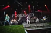Foreigner spielt auf einer Bühne mit roten Scheinwerfern und großem Bandbanner.
