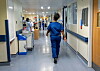 Pflegekräfte in blauen Uniformen gehen durch einen Krankenhausflur (Symbolbild).