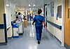Pflegekräfte in blauen Uniformen gehen durch einen Krankenhausflur (Symbolbild).