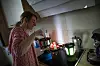 Frau kocht in der Küche mit Campingkocher, daneben Fondue-Set, Stövchen und Teelicht.