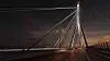 Beleuchtete Hängebrücke bei Nacht mit Lichtspuren auf der Fahrbahn