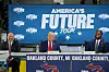 Donald Trump auf einer Bühne vor dem blauen Banner der America’s Future Tour in Oakland County, Michigan.