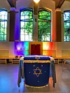 Wand hinter dem Torah-Schrein leuchtet in Regenbogenfarben