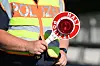 Ein Polizist steht mit einer Polizeikelle bereit.
