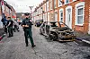 Polizisten inspizieren ausgebrannte Autos in einer Straße in Belfast.