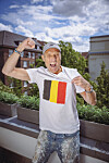 Roland Peeters jubelt auf einer Terrasse im Belgien-Trikot mit Flagge.