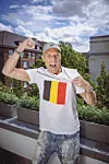 Roland Peeters jubelt auf einer Terrasse im Belgien-Trikot mit Flagge.