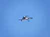 Eine Drohne fliegt im blauen, wolkenlosen Himmel und wird mit einem roten Kreis anvisiert
