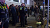 Anwohner und Polizisten verfolgen die Löscharbeiten, nachdem das Gebäude evakuiert wurde.